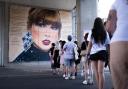 Swifties line up to pose in front of a mural outside Wembley, as they gather outside the Stadium in north west London, ahead of second night in the latest run of Taylor Swift Eras Tour concerts at the venue