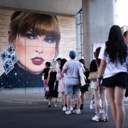 Swifties line up to pose in front of a mural outside Wembley, as they gather outside the Stadium in north west London, ahead of second night in the latest run of Taylor Swift Eras Tour concerts at the venue