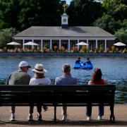 Morning visitors observe pedalo riders by the Serpentine in Hyde Park, London