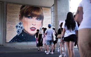 Swifties line up to pose in front of a mural outside Wembley, as they gather outside the Stadium in north west London, ahead of second night in the latest run of Taylor Swift Eras Tour concerts at the venue